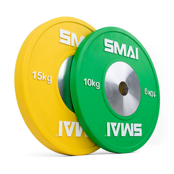 Two weight plates are displayed standing upright. One is yellow featuring "15 kg" and the other is green marked with "10 kg," both prominently displaying the SMAI brand and having a metal center. Designed for Olympic weightlifting, these competition bumper plates from the SMAI Competition Bumper Plate Set with Barbell - 50kg integrate seamlessly with any barbell setup.