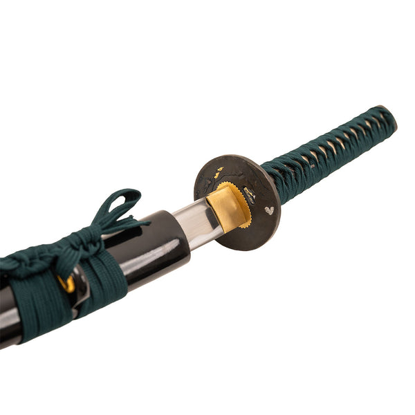 A close-up of the SMAI Katana - Medium Carbon Emerald shows its dark green-wrapped handle, round guard, and polished blade partially drawn from a black scabbard with matching cord—a striking katana for collectors or practitioners.