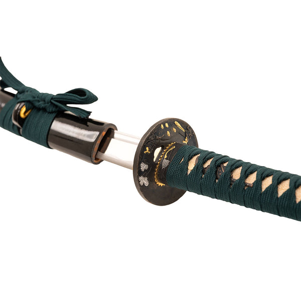 A close-up of the SMAI Katana - Medium Carbon Emerald reveals its ornate handguard and dark green braided handle, highlighting the fine craftsmanship of this medium carbon steel sword.