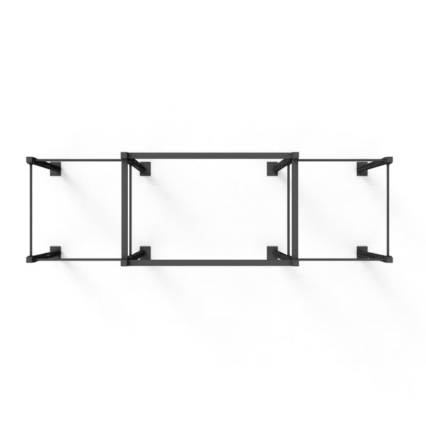 An overhead view of the Rig featuring four squat cells with a utility bridge in an X-frame design by No Sync To Channel Engine, showcasing its minimalist black metal and glass construction. The wall-mounted shelf comprises three rectangular sections with open sides, offering a sleek, modular aesthetic against a plain white background.