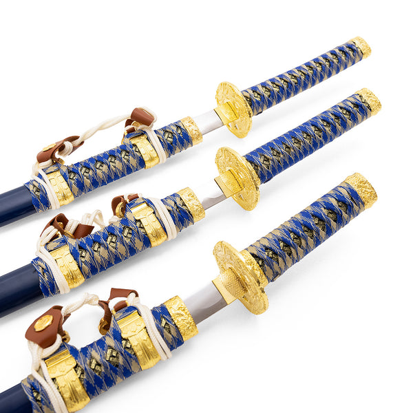 The SMAI Samurai 3pc Sword & Stand - Blue features three decorative Japanese swords with blue and gold braided handles and gold handguards, artistically arranged on a white background—one fully sheathed, two partially unsheathed.