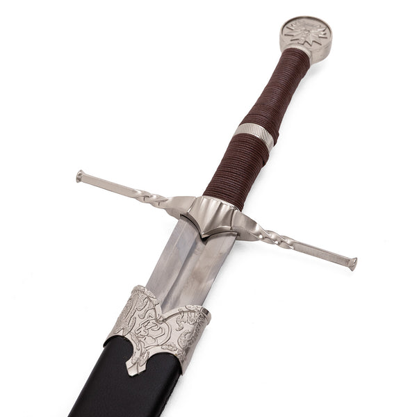 The SMAI Medieval Sword - Witch Hunter Deluxe features a silver crossguard and pommel, brown leather-wrapped handle, and ornate engraved sheath tip—ideal as a display broadsword or for cosplay sword enthusiasts.