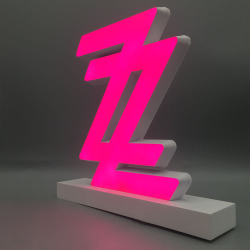 A neon pink zigzag-shaped light sits on a white rectangular base against a gray background.