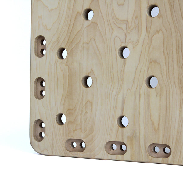 A close-up of the SMAI Monster Peg Board, crafted from light wood marine ply, displays rows of circular and oval holes in a grid pattern with smooth edges and natural grain texture.