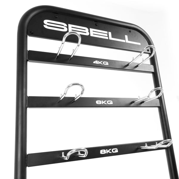 The SBELL Stand from Sbell Training is ideal for fitness enthusiasts, featuring a sleek and modern black metal weight rack with four labeled holders for kettlebells weighing 4kg, 6kg, and 8kg. Its rounded frame and metal hooks ensure secure gym organization.