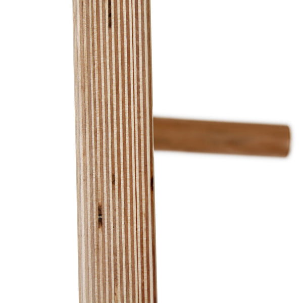Close-up of a vertical wooden plank with layered grain; in the background, a blurred horizontal rod suggests the SMAI Monster Peg Board marine ply pegboard, perfect for load bearing wall mount setups.