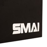A close-up of a black surface featuring the white “SMAI” logo in the lower right corner showcases the durable build of the SMAI Plyometric Box - Foam Covered - Black Series—an essential piece of equipment for box jumps and other explosive exercises.