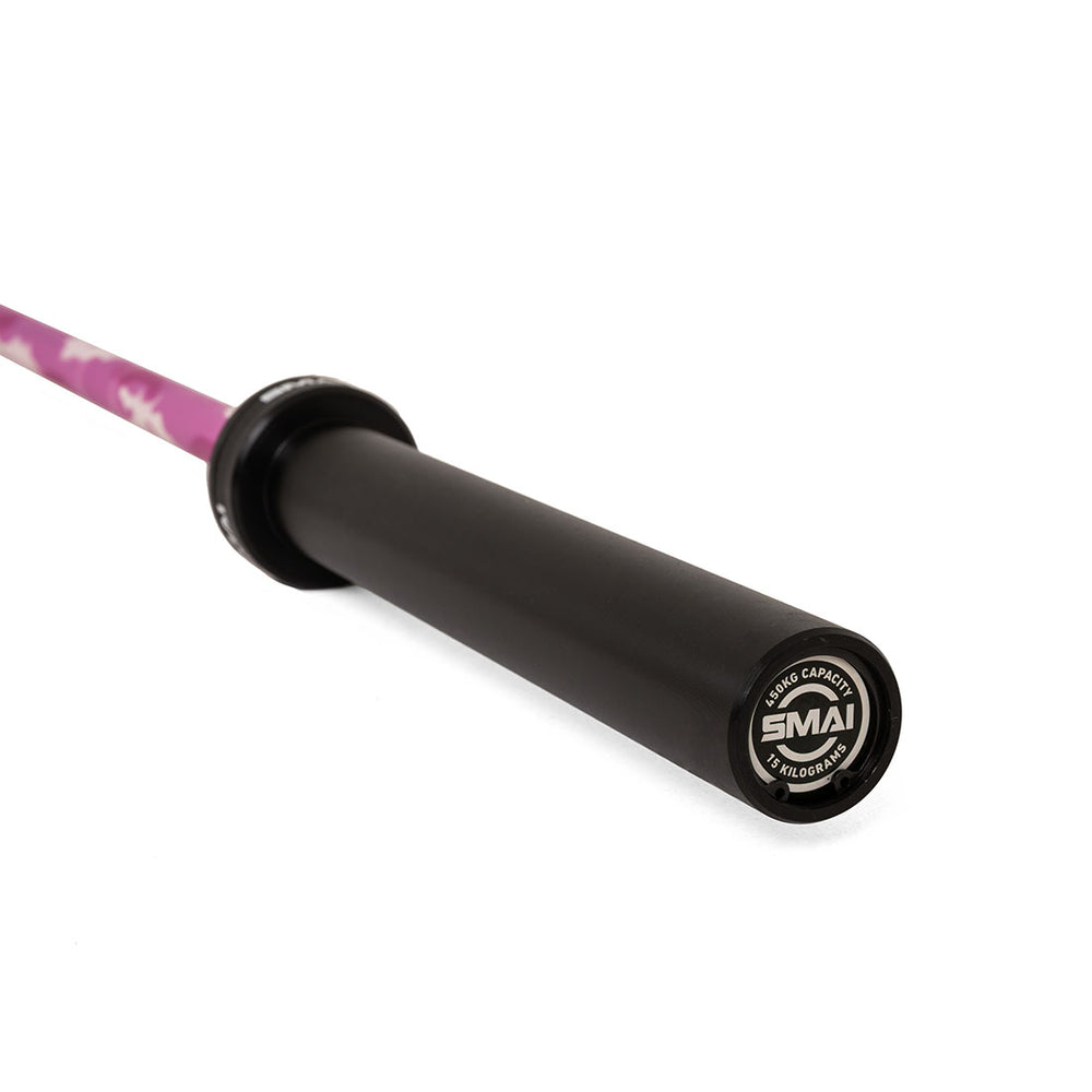 A close-up of the end of a black and pink camo SMAI Barbell, showcasing the logo and 15kg weight capacity details on the end cap, set against a white background. The Barbell - Pink Camo - 15kg combines style and performance for your training needs.