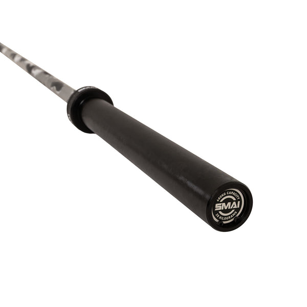 A close-up view of a grey camo coated barbell, specifically the SMAI Barbell - Grey Camo - 20kg, showing the end cap with the SMAI logo and part of the bar extending into the distance.