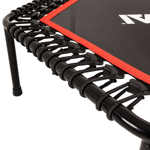Close-up of the SMAI Rebounder Mini Trampoline 50″ showcases its sturdy metal frame with bungee cords securely attaching the black jumping mat—a durable fitness trampoline featuring a distinctive red border.