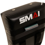 A close-up of the SMAI Kick Shield - Shoc Tec Curved, featuring sturdy straps, a silver handle, and impact absorbing foam for superior protection during training.