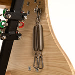 Close-up of two metal tension springs attached to the wooden frame and black metal support of the SMAI Pilates Chair, with visible screws and colored wires—designed for strength training and core conditioning.