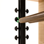 Close-up of a metal spring with curved hooks attached to the black frame of the SMAI Pilates Chair, next to a wooden platform—perfect for core conditioning and strength training—set against a white background.