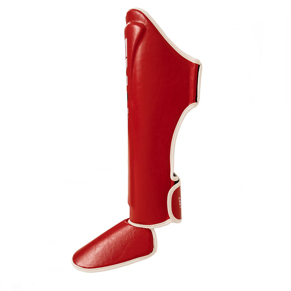 The SMAI Essentials Muay Thai Shin Instep Guard - Red, made of synthetic leather with white trim, protects the shin and foot. Shown against a white background.