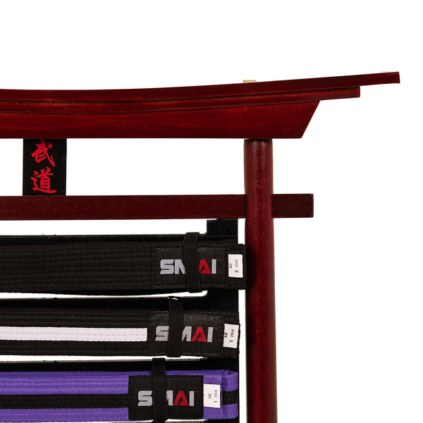 The SMAI Belt Display - Bushido Design features a wooden torii-inspired stand for black, white, and purple belts, with striking red Japanese kanji on a central black plaque—an elegant martial arts belt holder.
