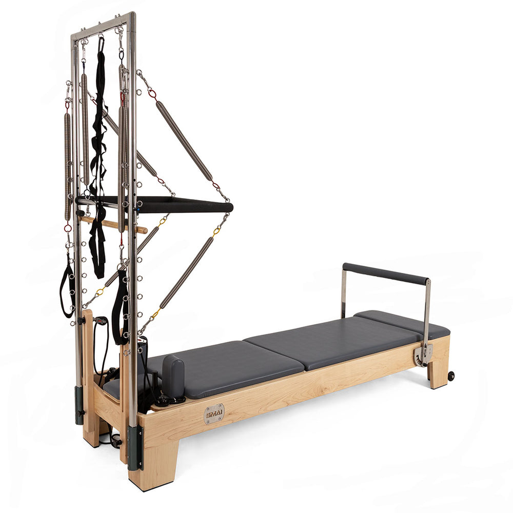 The SMAI Pilates - Classical Maple Reformer with Tower features a sturdy wooden frame, padded platform, and metal tower equipped with straps, springs, and resistance bands for versatile workouts.