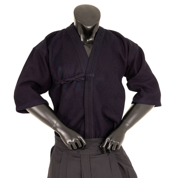 A black mannequin poses with hands on hips, dressed in the SMAI Deluxe Kendo Jacket—an indigo, double-layer keikogi made from 100% cotton—and pleated pants, set against a plain white background.