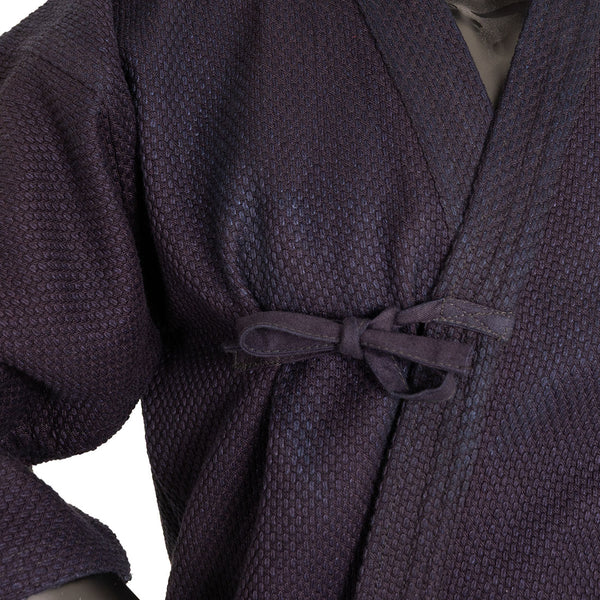 Close-up of the SMAI Deluxe Kendo Jacket - Indigo Double Layer Keikogi, expertly crafted from 100% cotton and fastened at the waist with a fabric bow. The detailed sleeve and collar features of this indigo keikogi jacket are clearly visible.