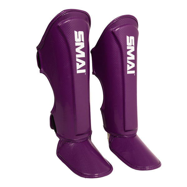 The Essentials Muay Thai Shin Instep Guard Kids - Purple by SMAI features a vibrant purple design with the brand name “SMAI” in white text. These shin and instep guards are specifically designed to provide reliable protection for young martial artists, making them an excellent choice for kids in need of quality martial arts gear.