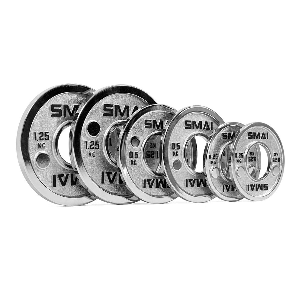 Six SMAI Calibrated Steel Change Plates of varying sizes, each clearly marked with the brand name and their specific weights (1.25 kg, 1 kg, 0.5 kg, and 0.25 kg), are neatly arranged side by side on a white background. These precisely calibrated steel plates provide accurate micro increment weight options, making them perfect for powerlifting progressions.