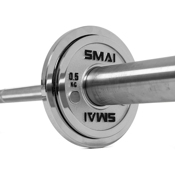 A close-up of a silver Olympic barbell with a 0.5 kg Calibrated Steel Change Plate by SMAI, engraved with the brand name, mounted on the end. The focus is on the plate and collar, showcasing the precision of these powerlifting calibrated plates as the bar extends out of frame.