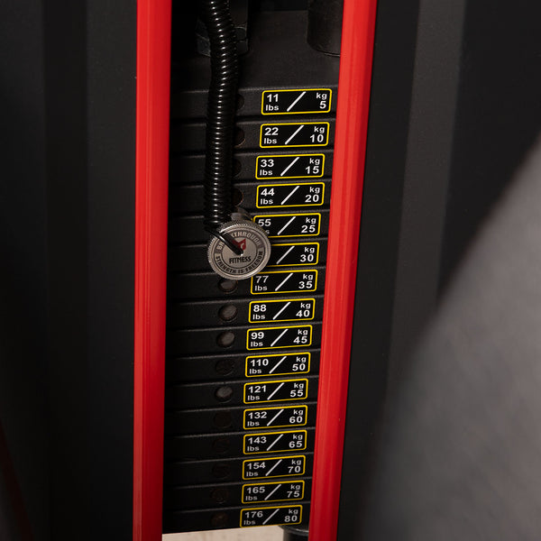 A close-up of the weight stack on the SMAI Leg Extension / Leg Curl Machine - 2 in 1, with clearly labeled weights in pounds and kilograms and the pin set at 44 lbs (20 kg), framed by the red and black structure of this commercial gym equipment.