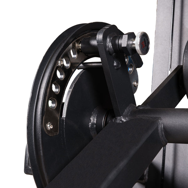 Close-up of the adjustment mechanism on the SMAI Leg Extension / Leg Curl Machine - 2 in 1, featuring a black metal knob, circular plate, and multiple holes for selecting resistance or position—components typically found on commercial gym equipment. The mechanism is isolated on a white background.
