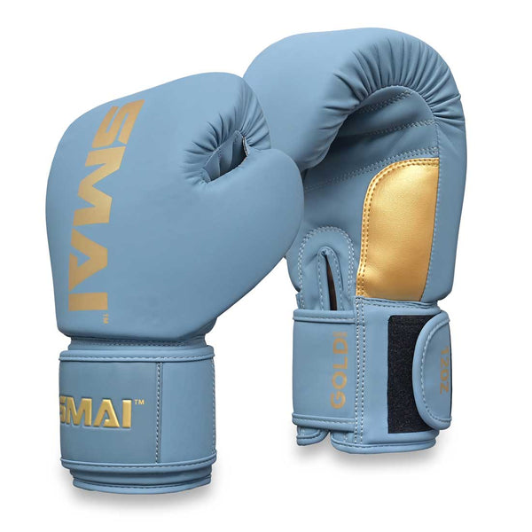 A pair of SMAI Gold Series Boxing Gloves in light blue with gold accents features black velcro straps for enhanced wrist support and displays the “SMAI” brand name in gold on both the wrist and top. One glove is positioned upright while the other is tilted forward.