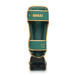 The SMAI Gold Series Muay Thai Shin Guards in green and gold, designed with "SMAI" and "LEFT" printed on them, feature multi-layer EVA protection, high-density foam for superior impact absorption, and multiple adjustable straps to ensure a secure fit. The shin guards are displayed against a white background.