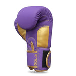 The SMAI Gold Series Boxing Glove in Purple/Gold is pictured upright, featuring visible stitching and a Velcro strap labeled "GOLD." Designed to provide optimal wrist support, these gloves deliver enhanced shock protection with every punch.