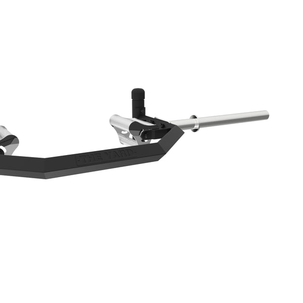 A close-up of the SMAI The Yard - Open Hex Trap Bar - Tri Grip Rotating Handle, featuring silver handles and "THE YARD" engraved on the side, designed for weightlifting, set against a plain white background.