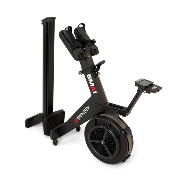 The SMAI AirMag X Rower in a black finish, featuring a large circular flywheel and a digital monitor, shown in a folded, upright storage position.