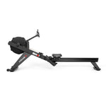 The SMAI AirMag X Rower is a black rowing machine with a large fan flywheel, a sliding seat, and a small electronic display mounted on the frame.