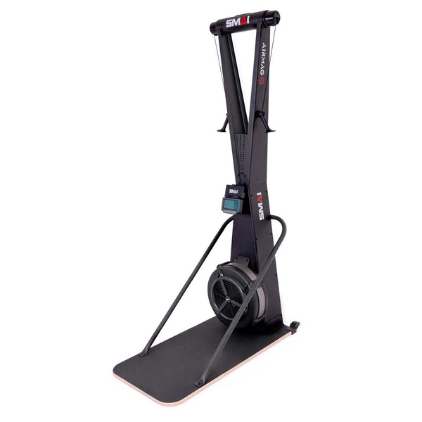A stationary SMAI AirMag X Skier with a vertical frame, digital display, and a fan resistance flywheel mounted on a floor platform.