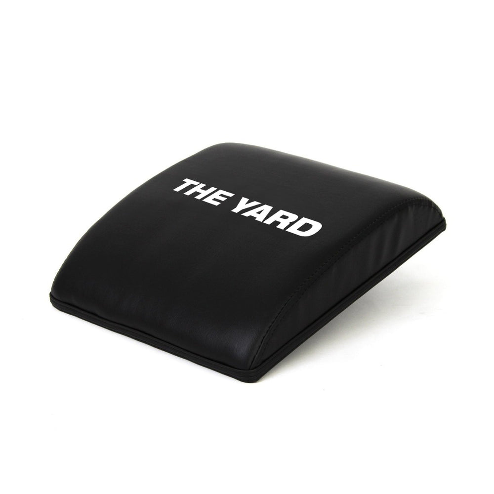 The SMAI The Yard - Ab Mat - Cross Training is a black, slightly curved pad with "THE YARD" in white on top, designed to support your lower back and enhance comfort during ab workouts and CrossFit routines.