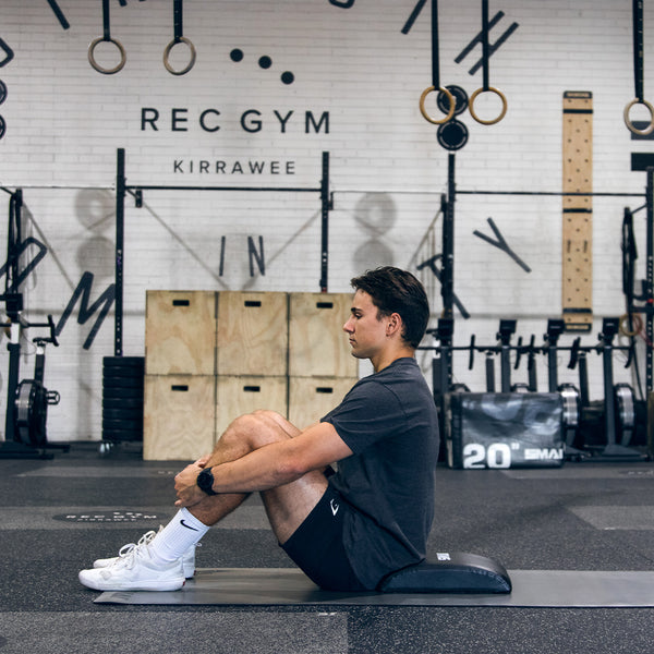 man in gym using Ab Mat, CrossFit Ab Mat, Abdominal Mat on a yoga mat sitting up