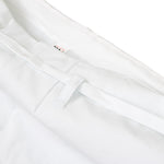 Close-up of white pants resembling the WKF Karate Uniform - Premium Kata Gi by SMAI; features include a sleek, slightly shiny fabric with prominent stitching and a waistband with belt loops. The tag inside partially reveals a logo inspired by the Karate Federation.