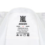 Close-up of a white martial arts uniform label with "Arashi" and Kanji, stating "WKF Karate Uniform - Premium Kata Gi," made of 65% Polyester and 35% Cotton. It includes care symbols for washing and is WKF Approved, ensuring quality assurance and authenticity under the brand SMAI.
