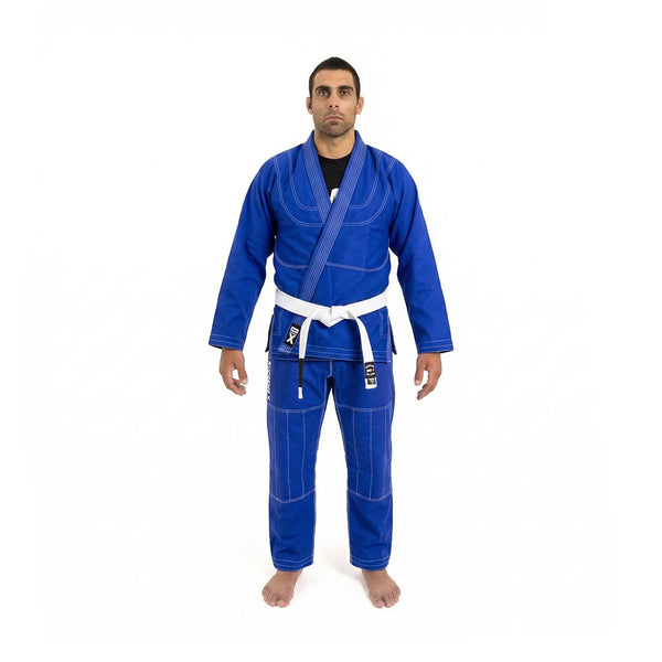 A person stands barefoot on a white background, wearing the SMAI Supreme X Brazilian Jiu Jitsu Uniform in blue with pearl weave jacket, Rip Stop pants, and a white belt, arms relaxed at their sides and facing forward.