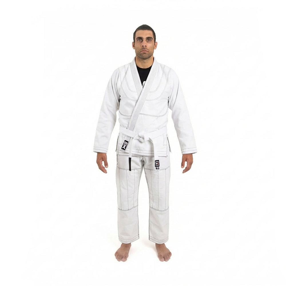 A person stands barefoot facing forward, wearing the SMAI Supreme X Brazilian Jiu Jitsu Uniform in white with a matching belt, made of pearl weave fabric, against a plain white background.