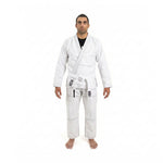 A person stands barefoot facing forward, wearing the SMAI Supreme X Brazilian Jiu Jitsu Uniform in white with a matching belt, made of pearl weave fabric, against a plain white background.