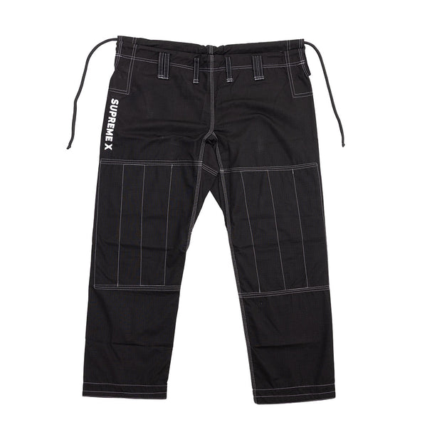 The SMAI Supreme X Brazilian Jiu Jitsu Uniform pants in black have reinforced stitching, an elastic waistband with drawstrings, belt loops, and "SUPREMEX" text printed vertically on the left hip. Shown laid flat on a white background.