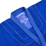 A close-up of the Supreme X Brazilian Jiu Jitsu Uniform - Blue by SMAI, featuring durable pearl weave fabric, reinforced stitching, and an inner collar label showing "SUPREME X, A3, PREMIUM BJJ, 65% COTTON, 35% POLYESTER, SMAI.