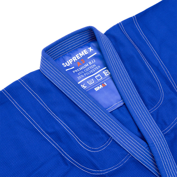 A close-up of the Supreme X Brazilian Jiu Jitsu Uniform - Blue by SMAI, featuring durable pearl weave fabric, reinforced stitching, and an inner collar label showing "SUPREME X, A3, PREMIUM BJJ, 65% COTTON, 35% POLYESTER, SMAI.