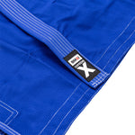 Close-up of the SMAI Supreme X Brazilian Jiu Jitsu Uniform in blue, crafted from durable pearl weave fabric with white stitching and a black "SMAI Supreme X" label near the edge.