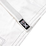Close-up of the SMAI Supreme X Brazilian Jiu Jitsu Uniform in white, featuring black stitching, a "SMAI Supreme X" lapel patch, textured pearl weave fabric, and reinforced seams for durability.