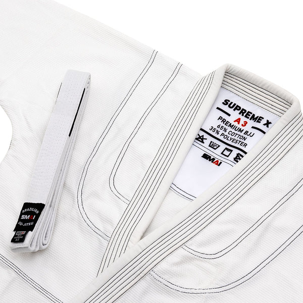 A white SMAI Supreme X Brazilian Jiu Jitsu Uniform, neatly folded with matching belt, features black stitching on pearl weave fabric and a collar label noting 65% cotton/35% polyester.
