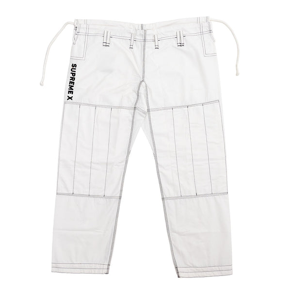 The Supreme X Brazilian Jiu Jitsu Uniform - White by SMAI features black stitching, knee reinforcement patches, belt loops, drawstring waist, and "SUPREMEX" printed vertically on the left thigh, all made from durable Rip Stop fabric.