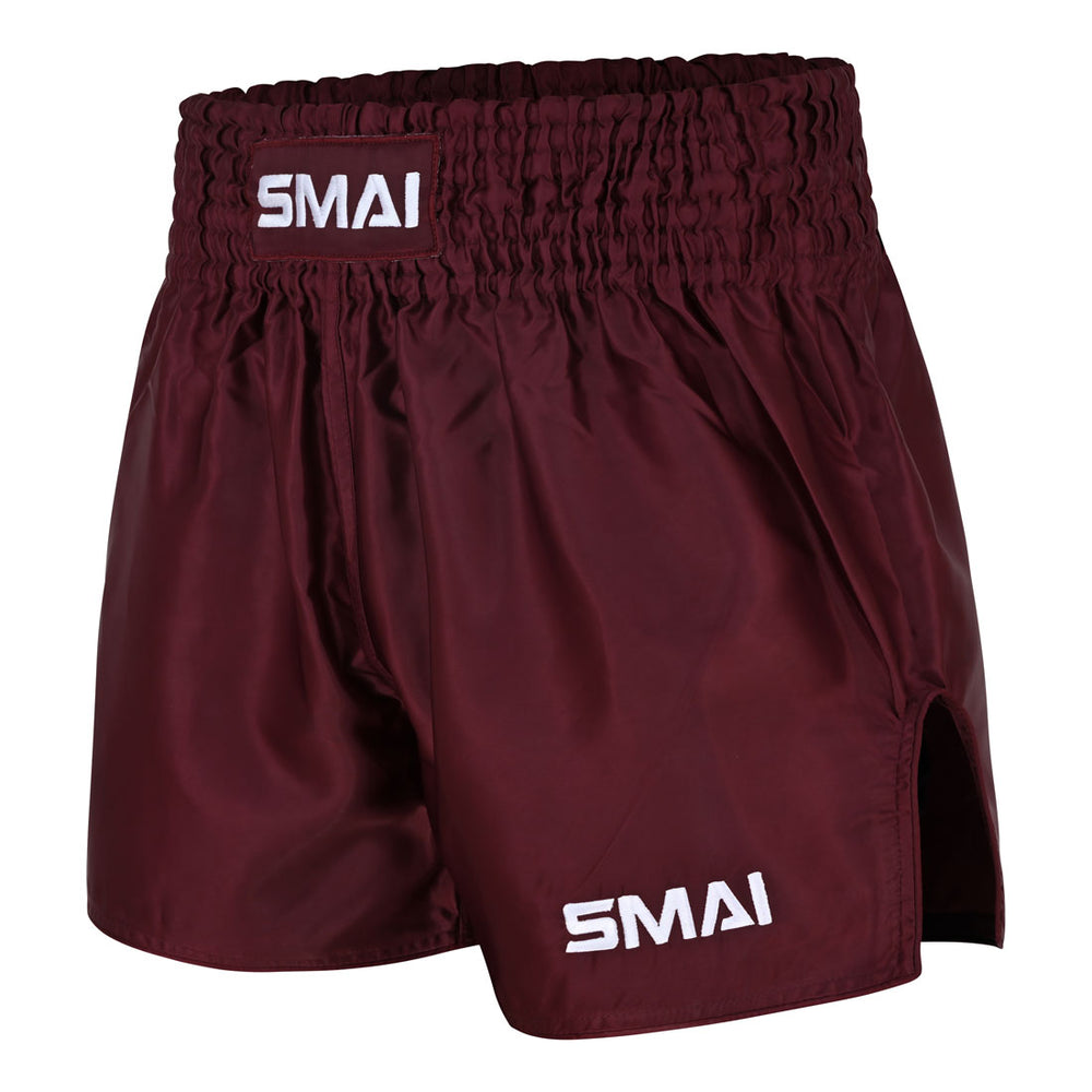 The SMAI Muay Thai Shorts - Burgundy are unisex satin polyester shorts featuring “SMAI” in white on the waistband and lower left leg. With an elastic waistband and side slits for enhanced movement, they are designed to provide comfort and freedom during training or competition.