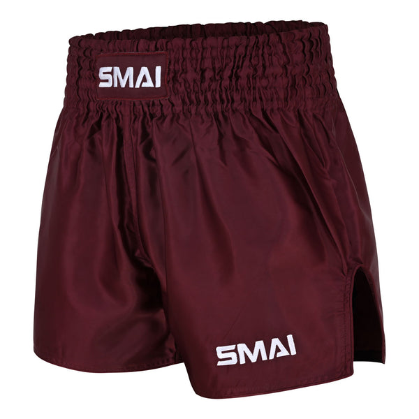 The SMAI Muay Thai Shorts - Burgundy are unisex satin polyester shorts featuring “SMAI” in white on the waistband and lower left leg. With an elastic waistband and side slits for enhanced movement, they are designed to provide comfort and freedom during training or competition.